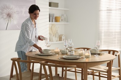 Photo of Woman setting table for dinner at home