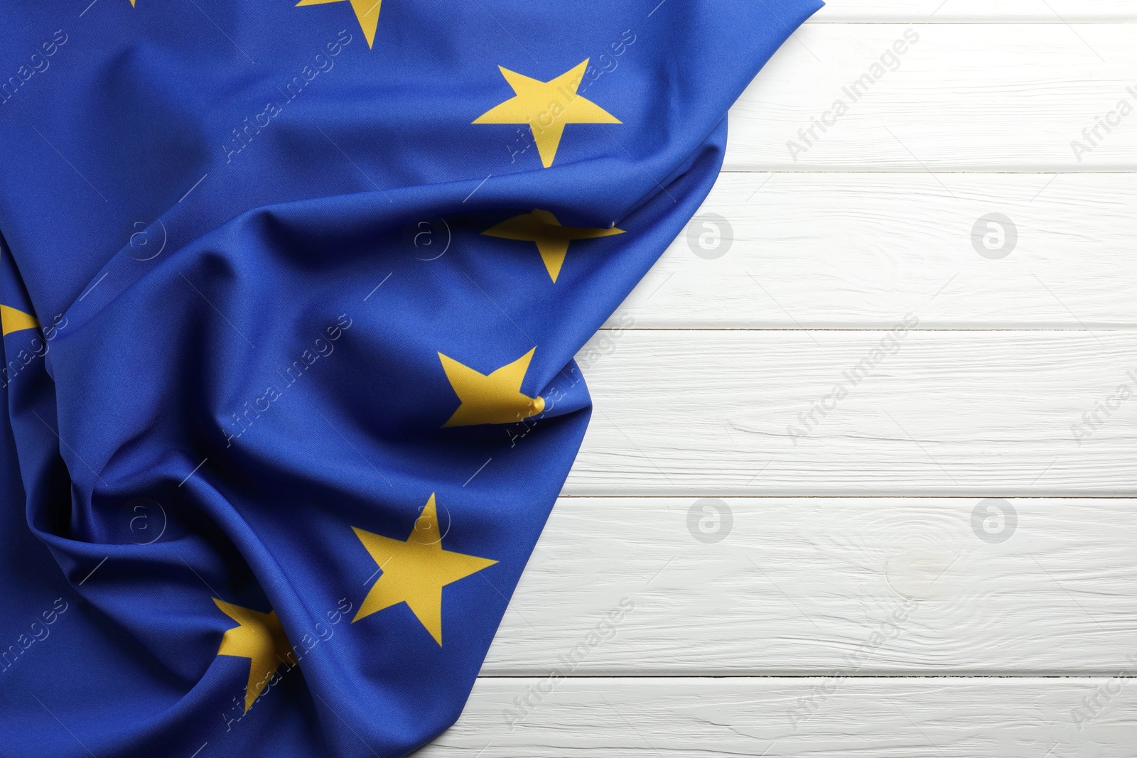 Photo of Flag of European Union on white wooden table, top view. Space for text