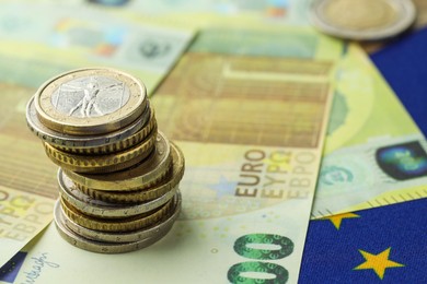 Photo of Euro banknotes and coins on European Union flag, closeup