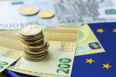 Photo of Euro banknotes and coins on European Union flag, closeup