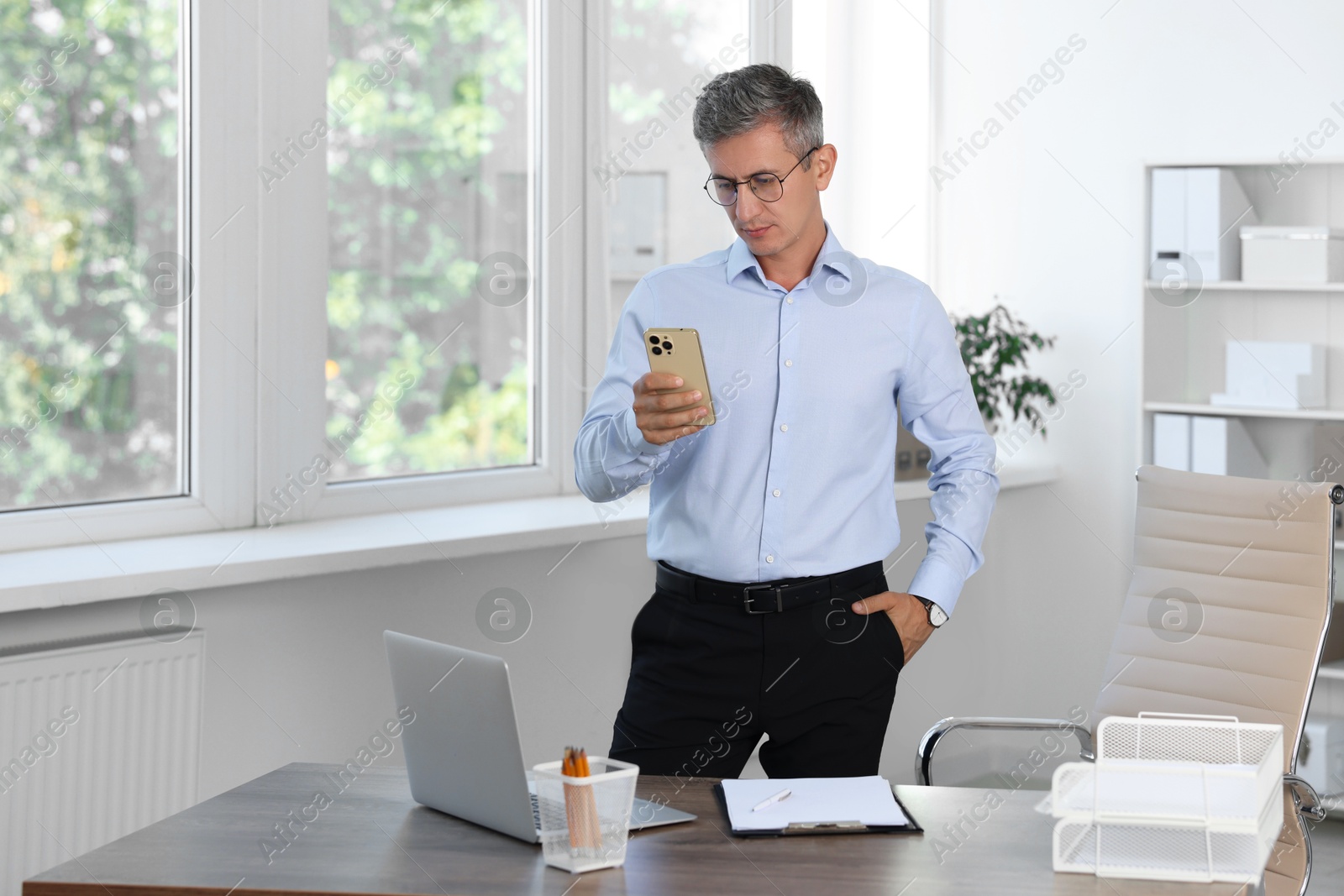 Photo of Middle aged man using smartphone in office