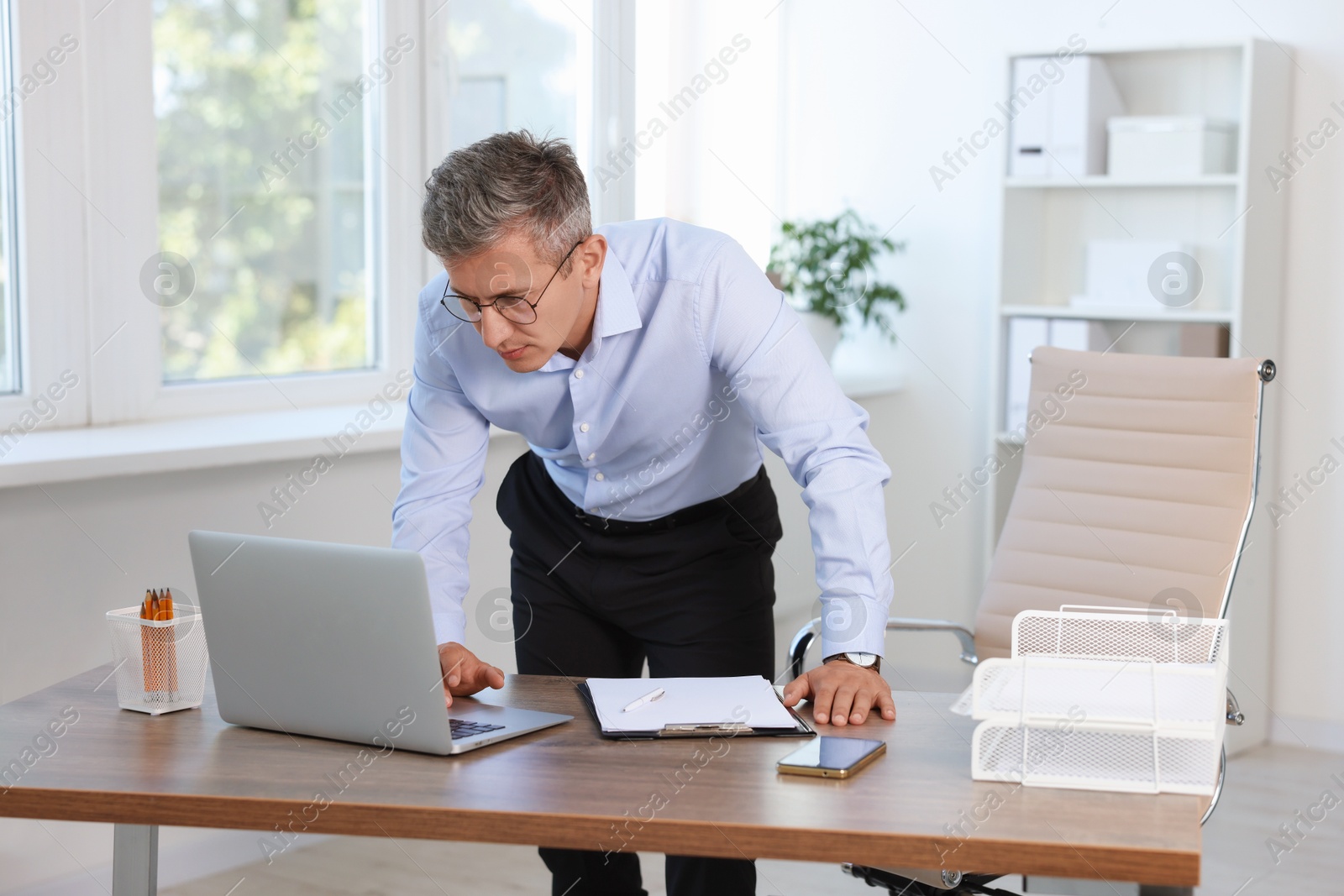 Photo of Middle aged man working with laptop in office