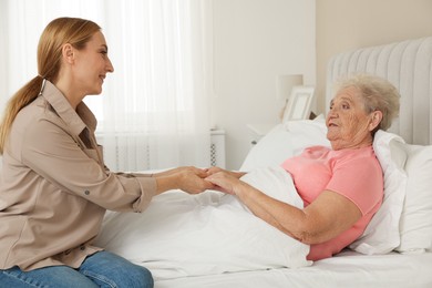 Photo of Caregiver supporting senior patient in bedroom at home