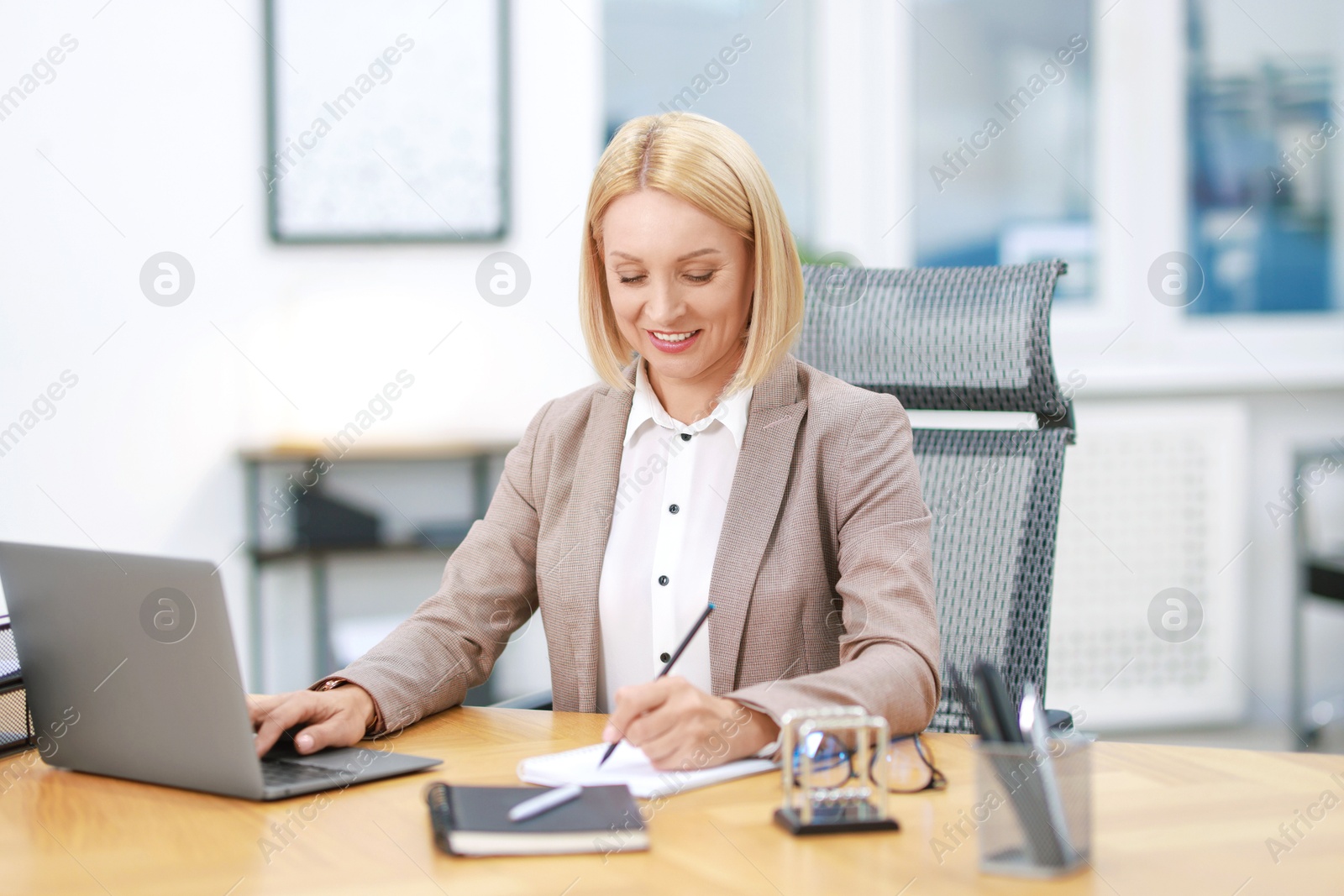 Photo of Smiling middle aged woman working at table in office