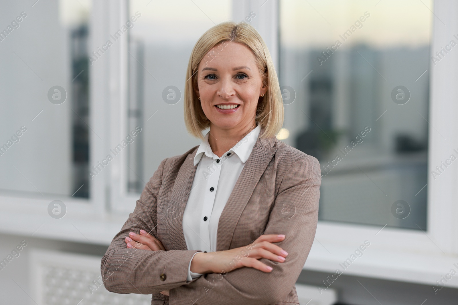 Photo of Portrait of smiling middle aged woman with crossed arms in office