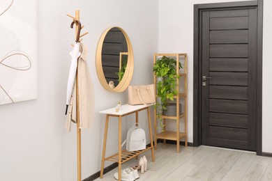 Clothing rack, mirror, houseplant, storage bench and shelving unit in hallway