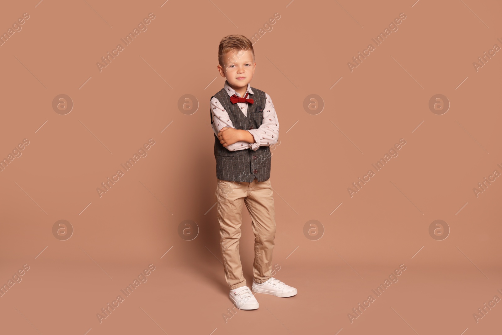 Photo of Full length portrait of little boy with stylish clothes on brown background