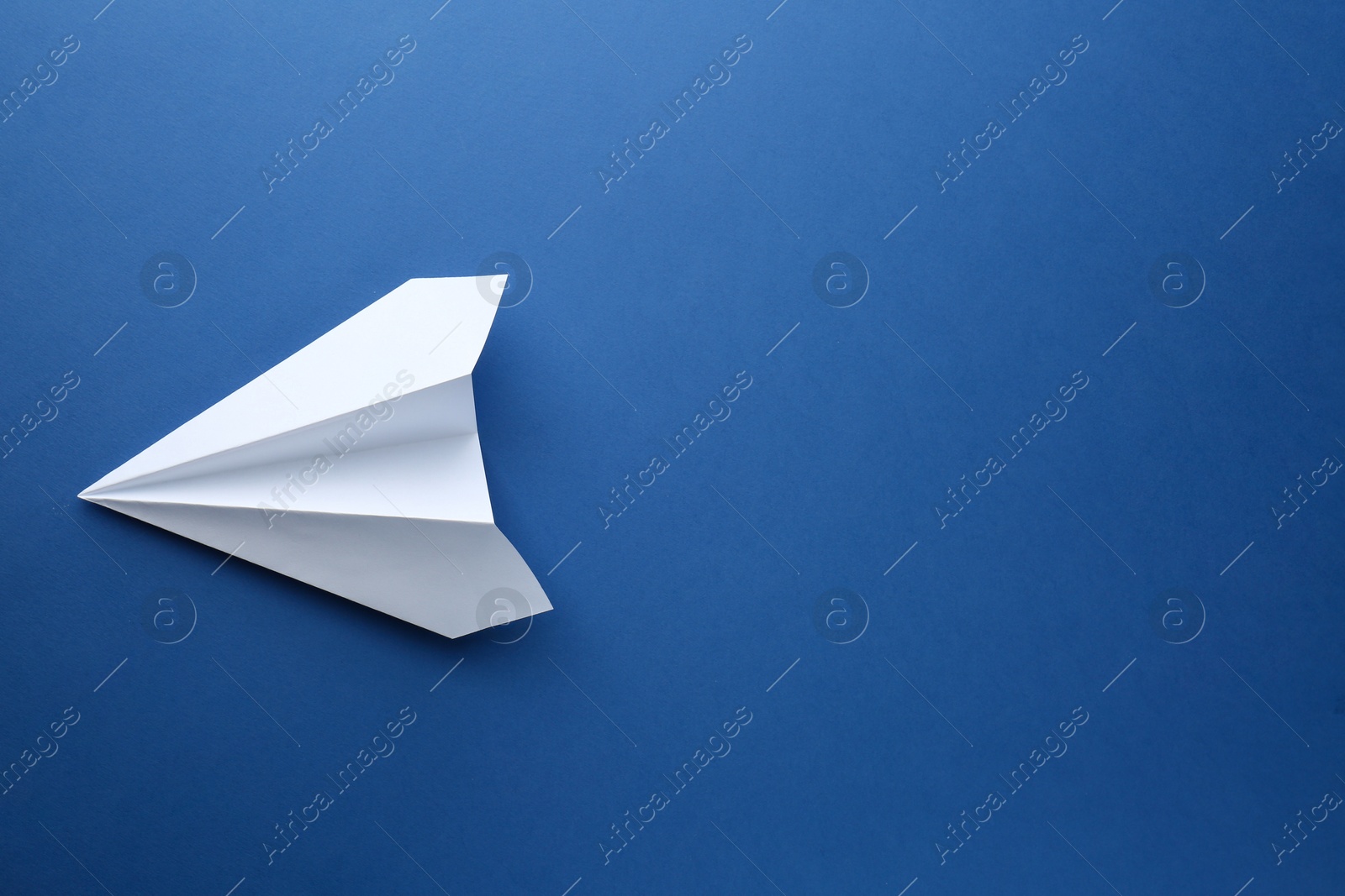 Photo of One handmade paper plane on blue background, top view. Space for text