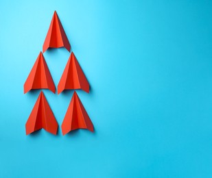 Photo of Handmade red paper planes on light blue background, top view. Space for text