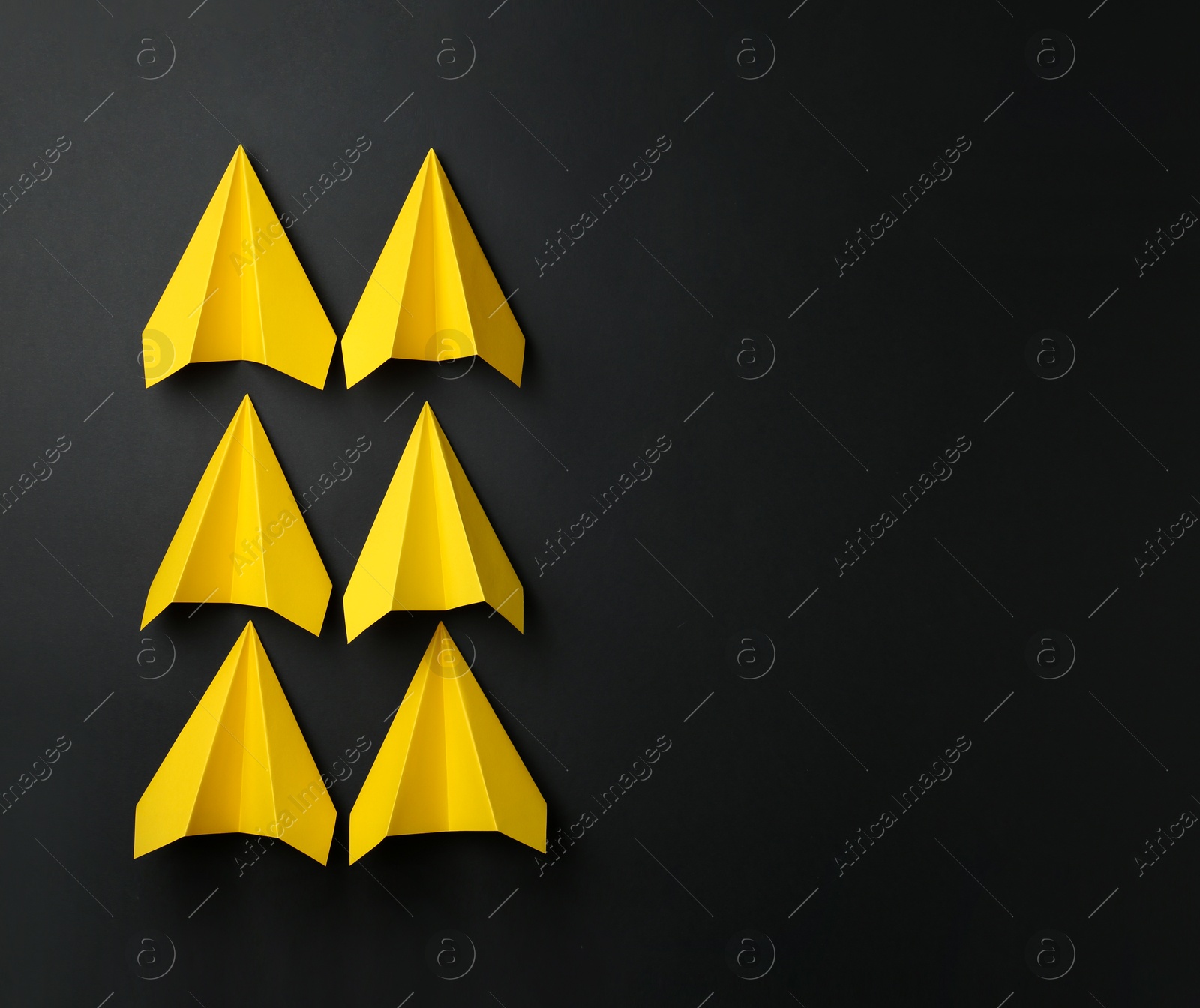 Photo of Handmade yellow paper planes on black background, top view. Space for text