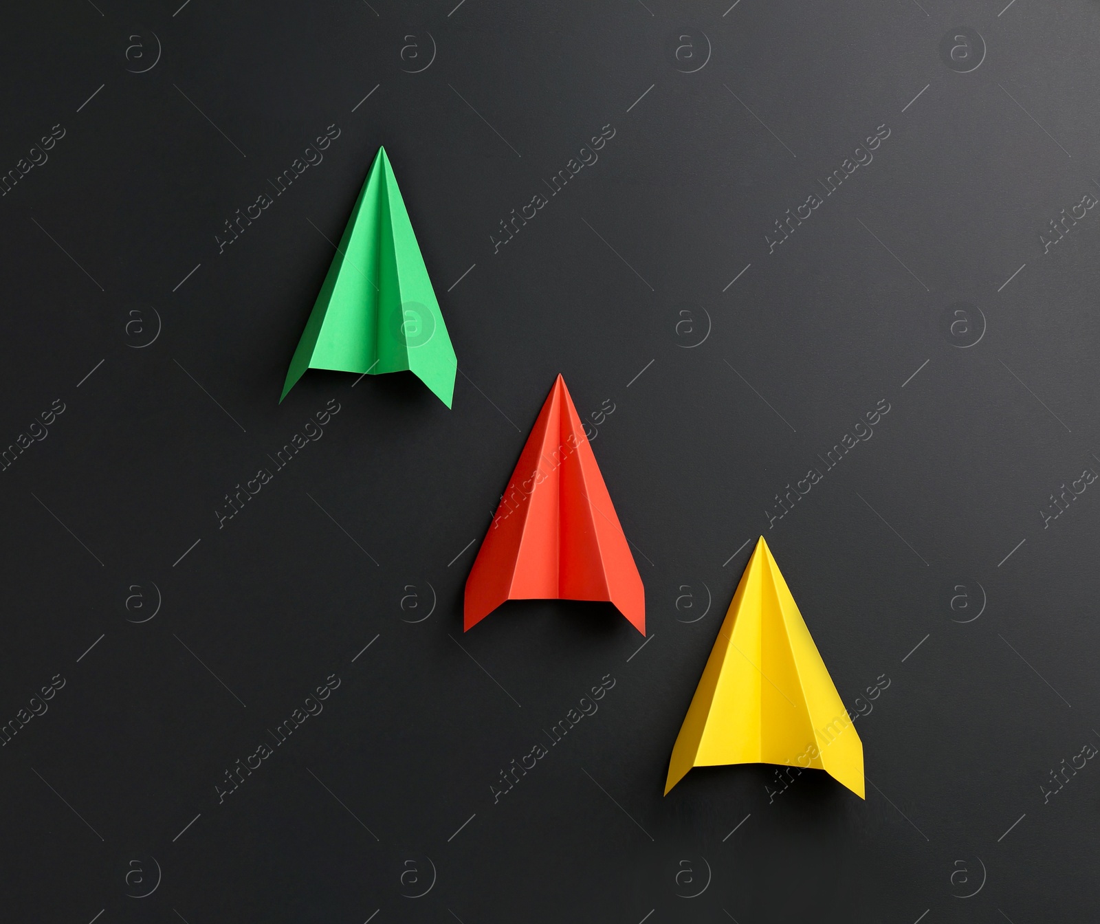 Photo of Handmade color paper planes on black background, flat lay