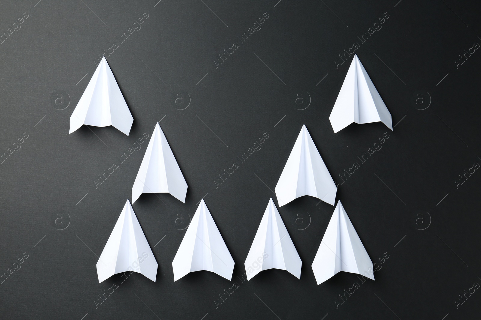 Photo of White paper planes on black background, top view