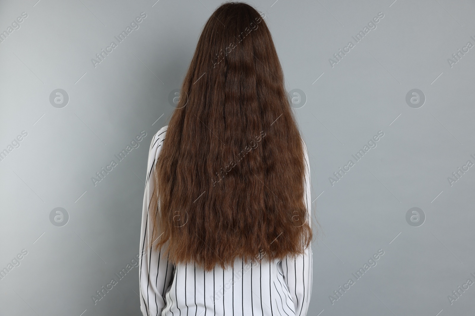 Photo of Teenage girl with healthy long hair on light grey background, back view