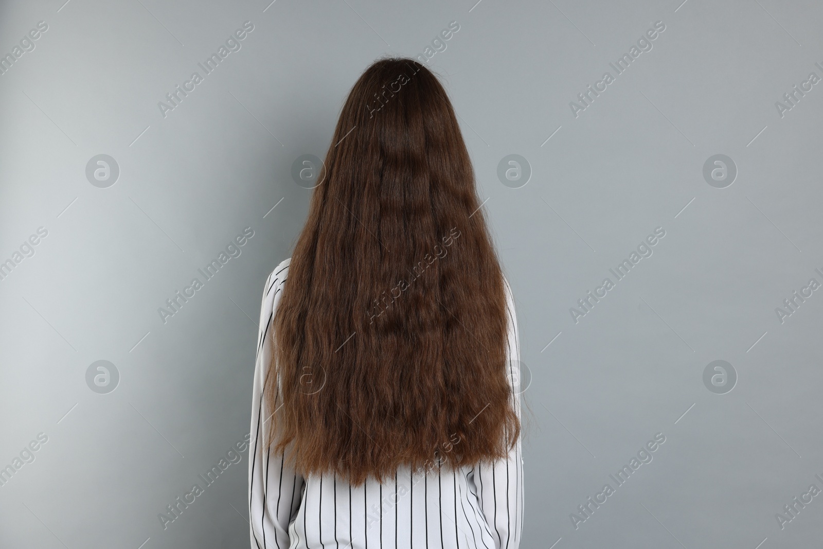 Photo of Teenage girl with healthy long hair on light grey background, back view