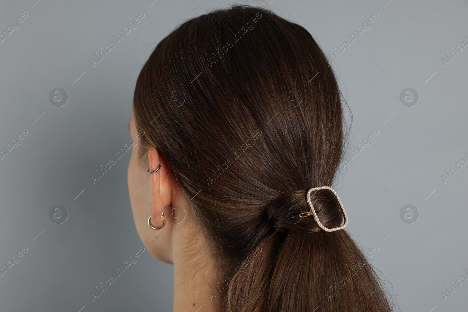 Photo of Teenage girl with stylish hair clip on light grey background, back view