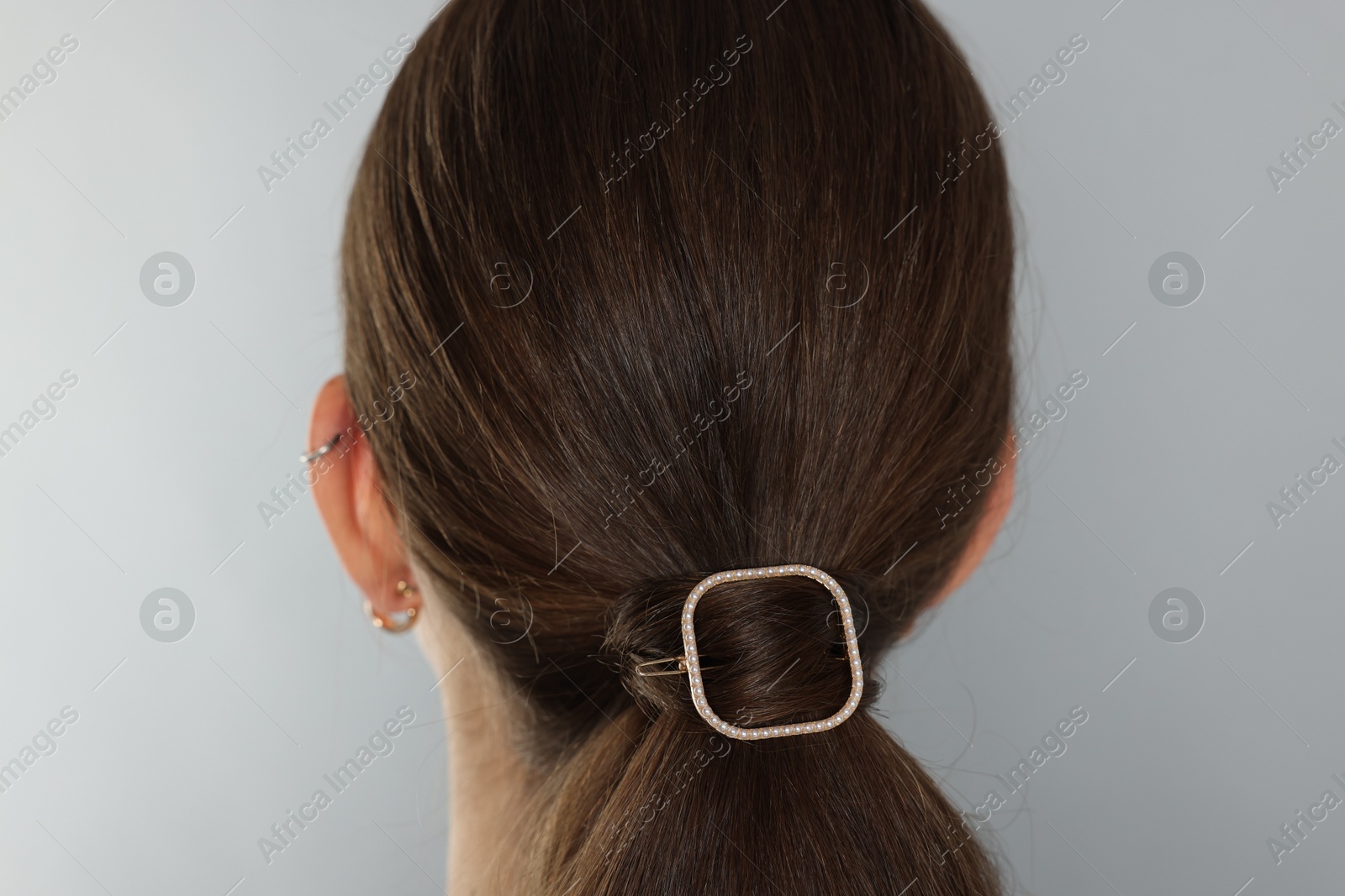 Photo of Teenage girl with stylish hair clip on light grey background, back view