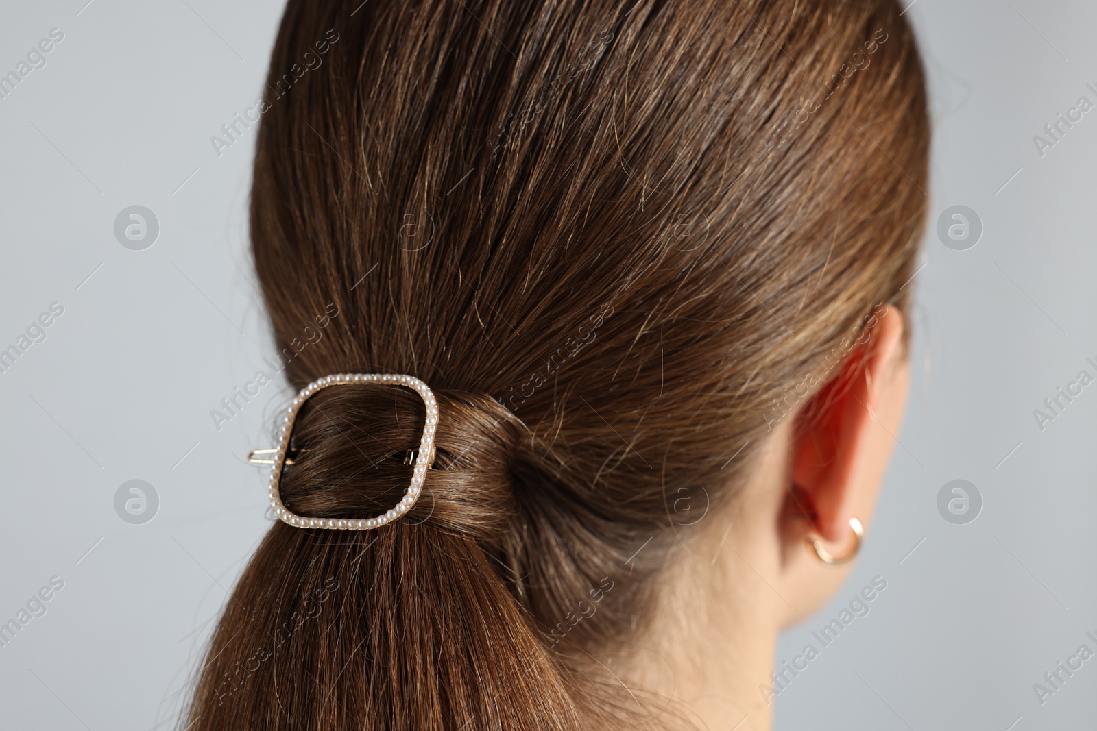 Photo of Teenage girl with stylish hair clip on light grey background, back view