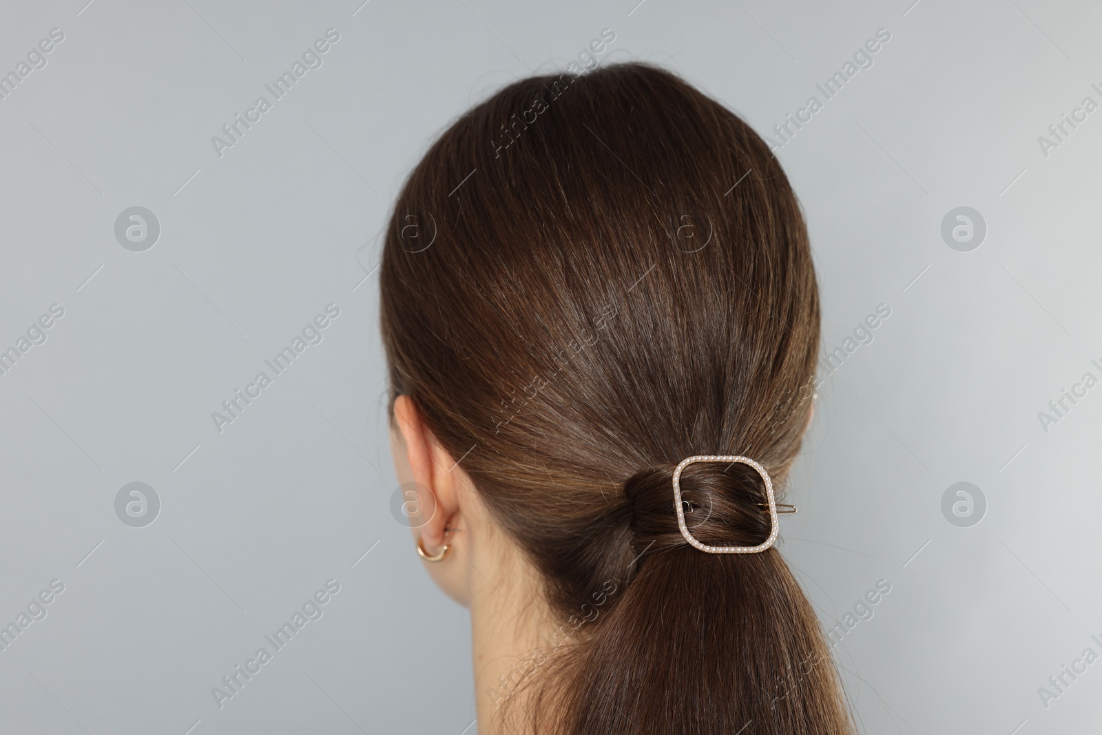 Photo of Teenage girl with stylish hair clip on light grey background, back view