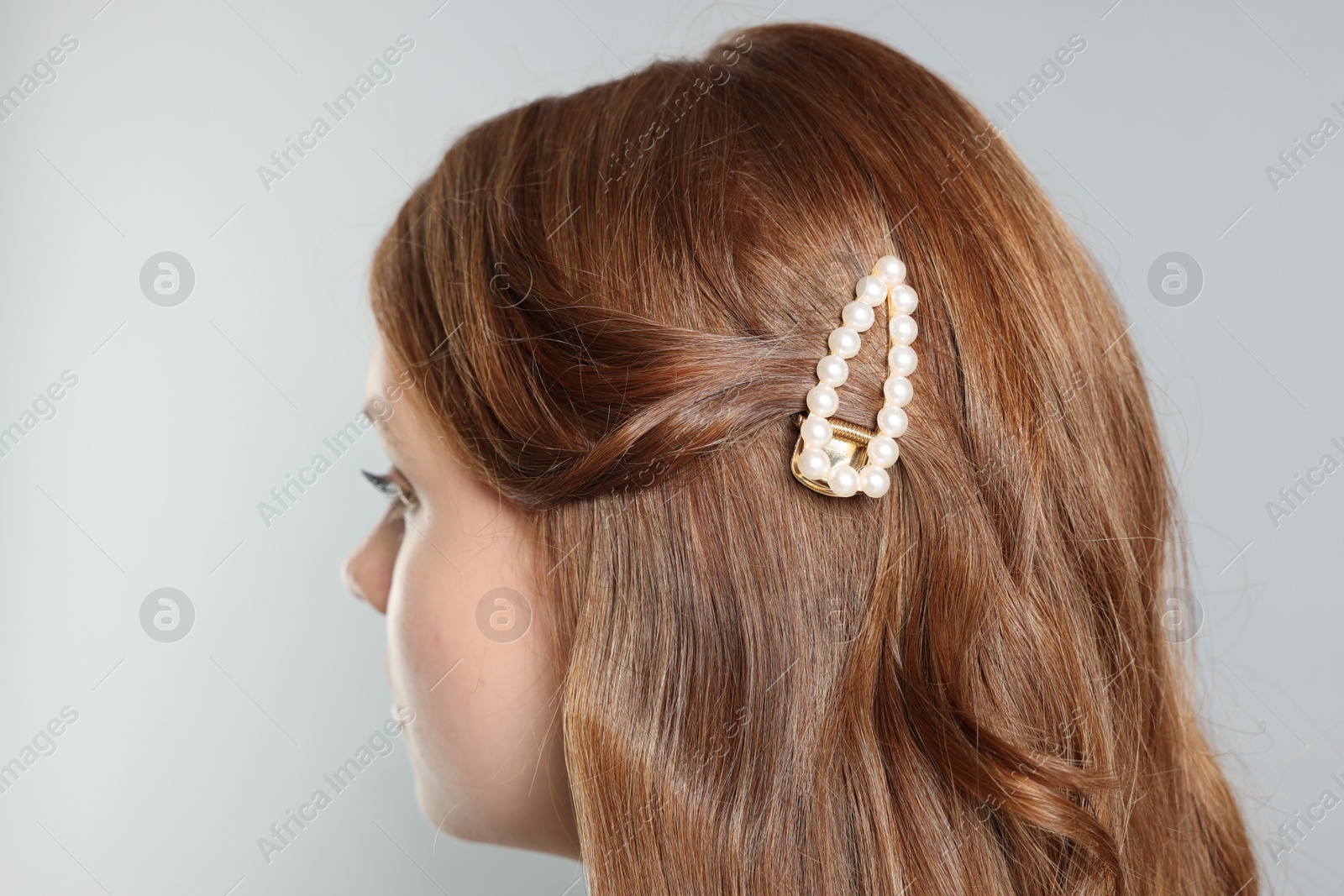 Photo of Teenage girl with stylish hair clip on light grey background, closeup