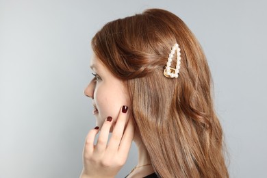 Photo of Teenage girl with stylish hair clip on light grey background