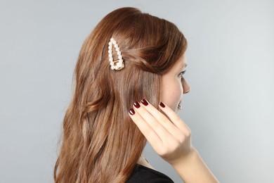 Photo of Teenage girl with stylish hair clip on light grey background