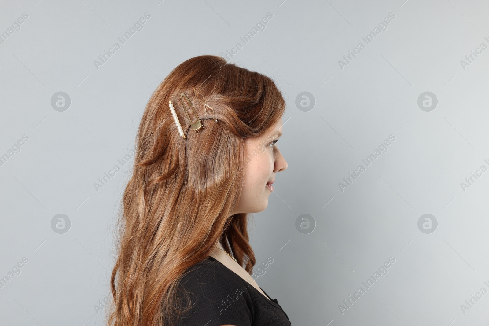 Photo of Teenage girl with stylish hair clips on light grey background. Space for text