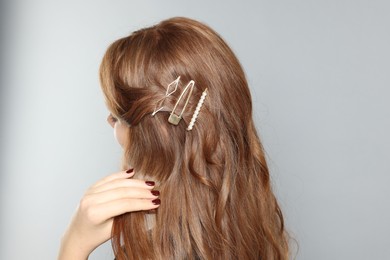 Photo of Teenage girl with stylish hair clips on light grey background, back view