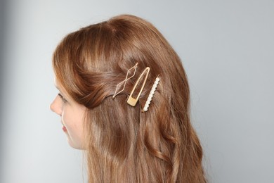 Teenage girl with stylish hair clips on light grey background