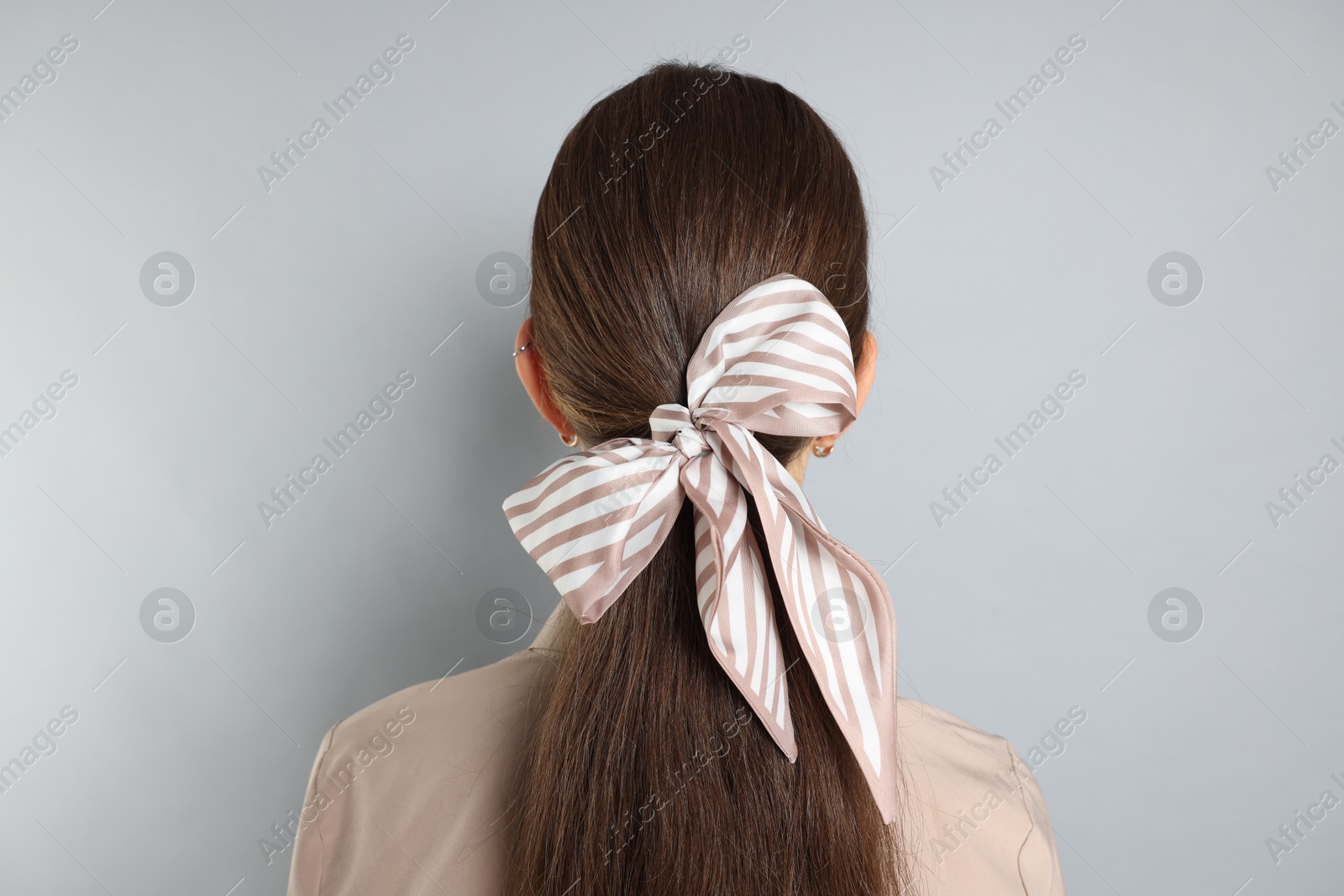 Photo of Teenage girl with stylish hair band on light grey background, back view