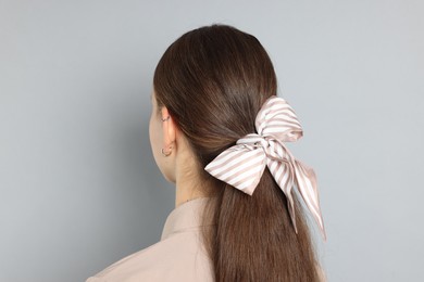 Teenage girl with stylish hair band on light grey background, back view