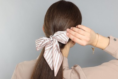 Photo of Teenage girl with stylish hair band on light grey background, back view