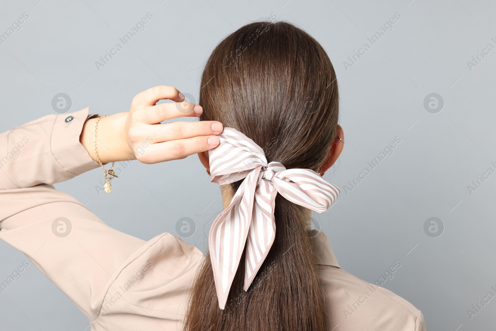 Photo of Teenage girl with stylish hair band on light grey background, back view