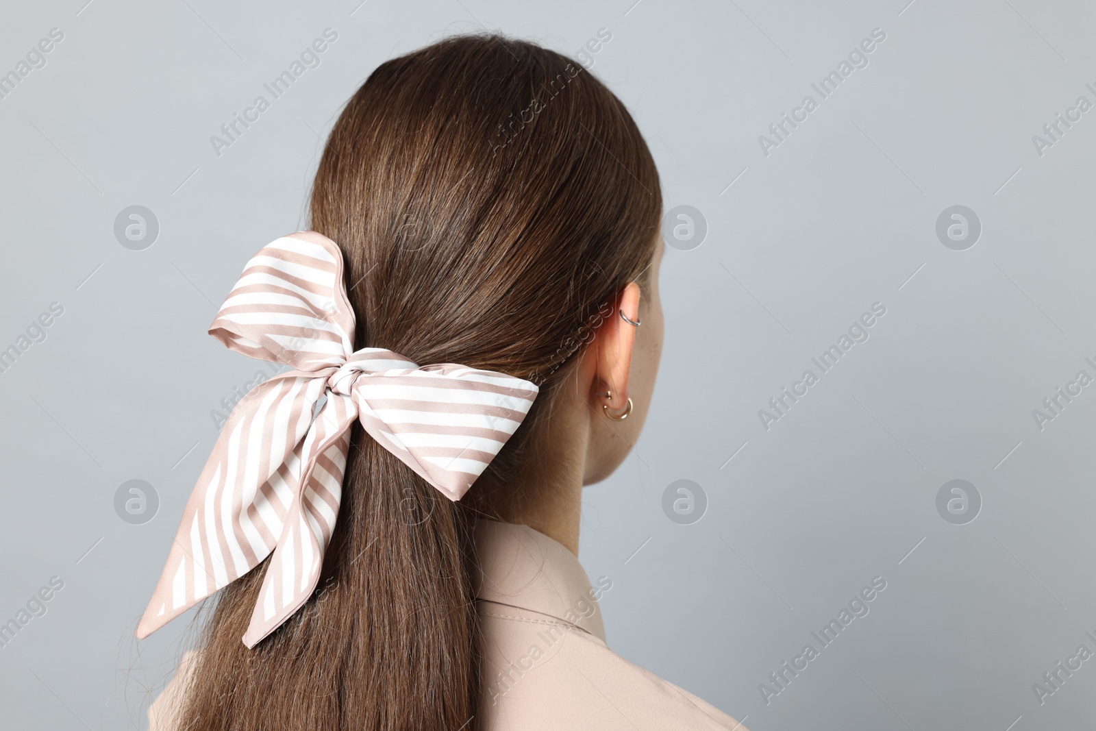 Photo of Teenage girl with stylish hair band on light grey background, back view. Space for text