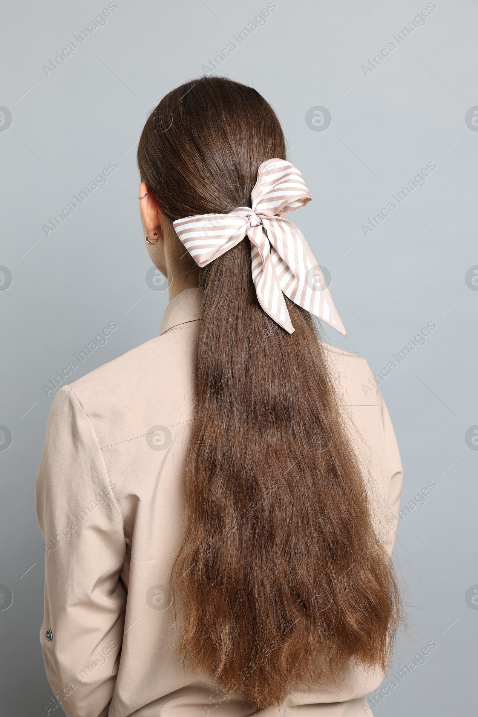 Photo of Teenage girl with stylish hair band on light grey background, back view