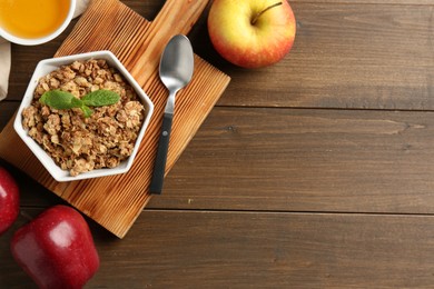 Photo of Tasty apple crisp in bowl, fresh fruits, honey and spoon on wooden table, flat lay. Space for text