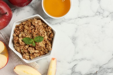 Photo of Tasty apple crisp in bowl, fresh fruits and honey on white marble table, flat lay. Space for text