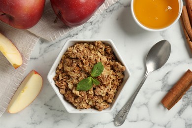 Photo of Tasty apple crisp in bowl, ingredients and spoon on white marble table, flat lay