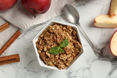 Photo of Tasty apple crisp in bowl, ingredients and spoon on white marble table, flat lay