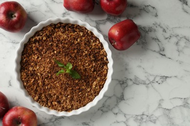 Photo of Tasty apple crisp in baking dish and fresh fruits on white marble table, flat lay. Space for text