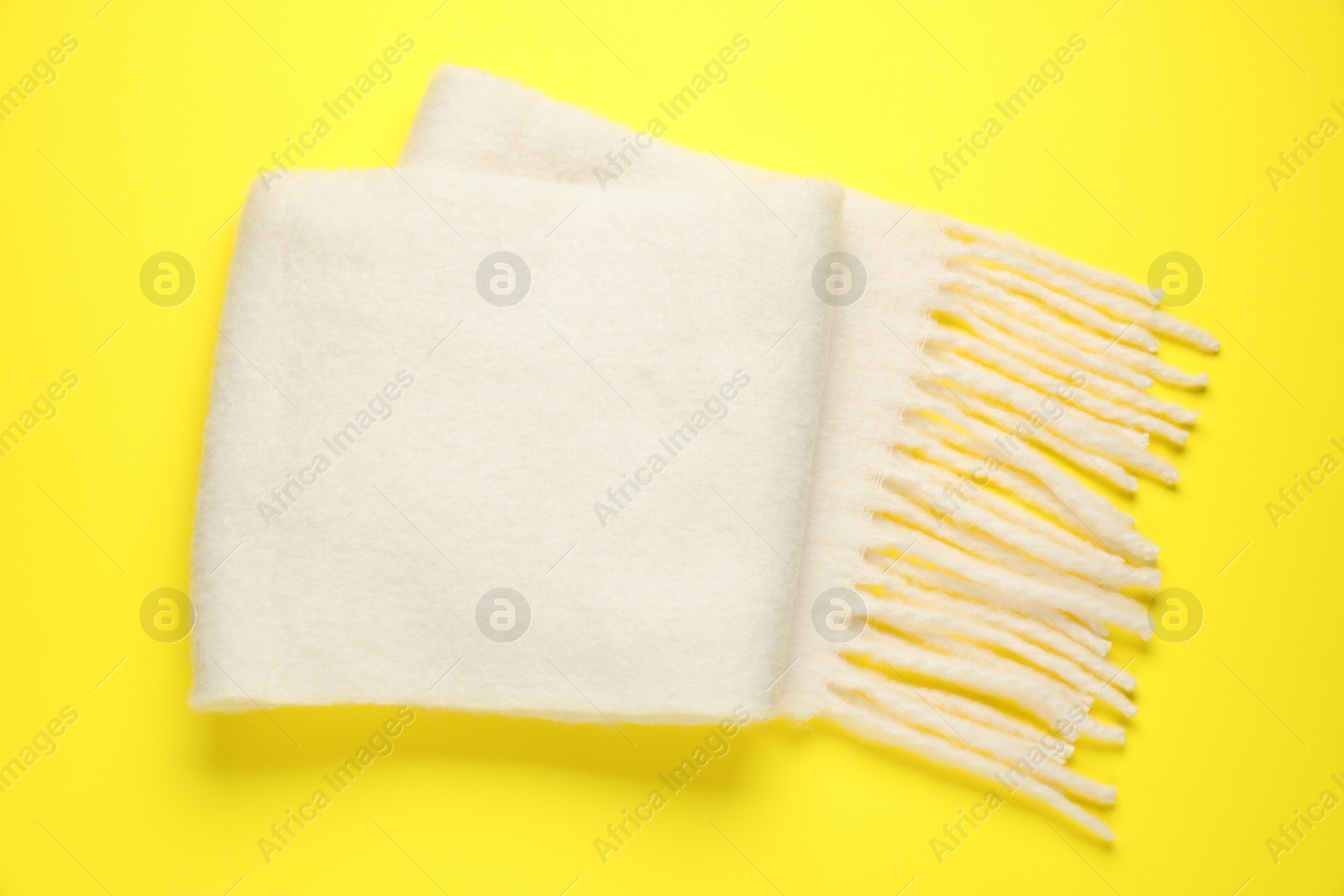 Photo of Warm woolen scarf on yellow background, top view