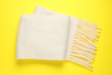 Photo of Warm woolen scarf on yellow background, top view