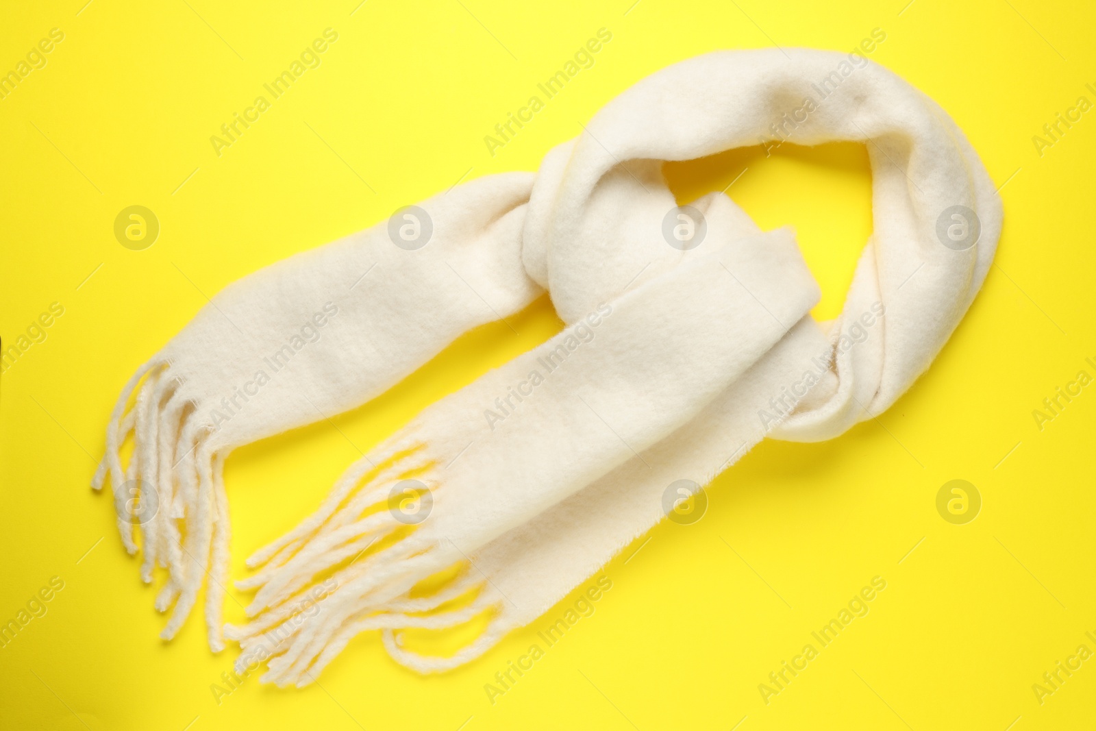 Photo of Warm woolen scarf on yellow background, top view