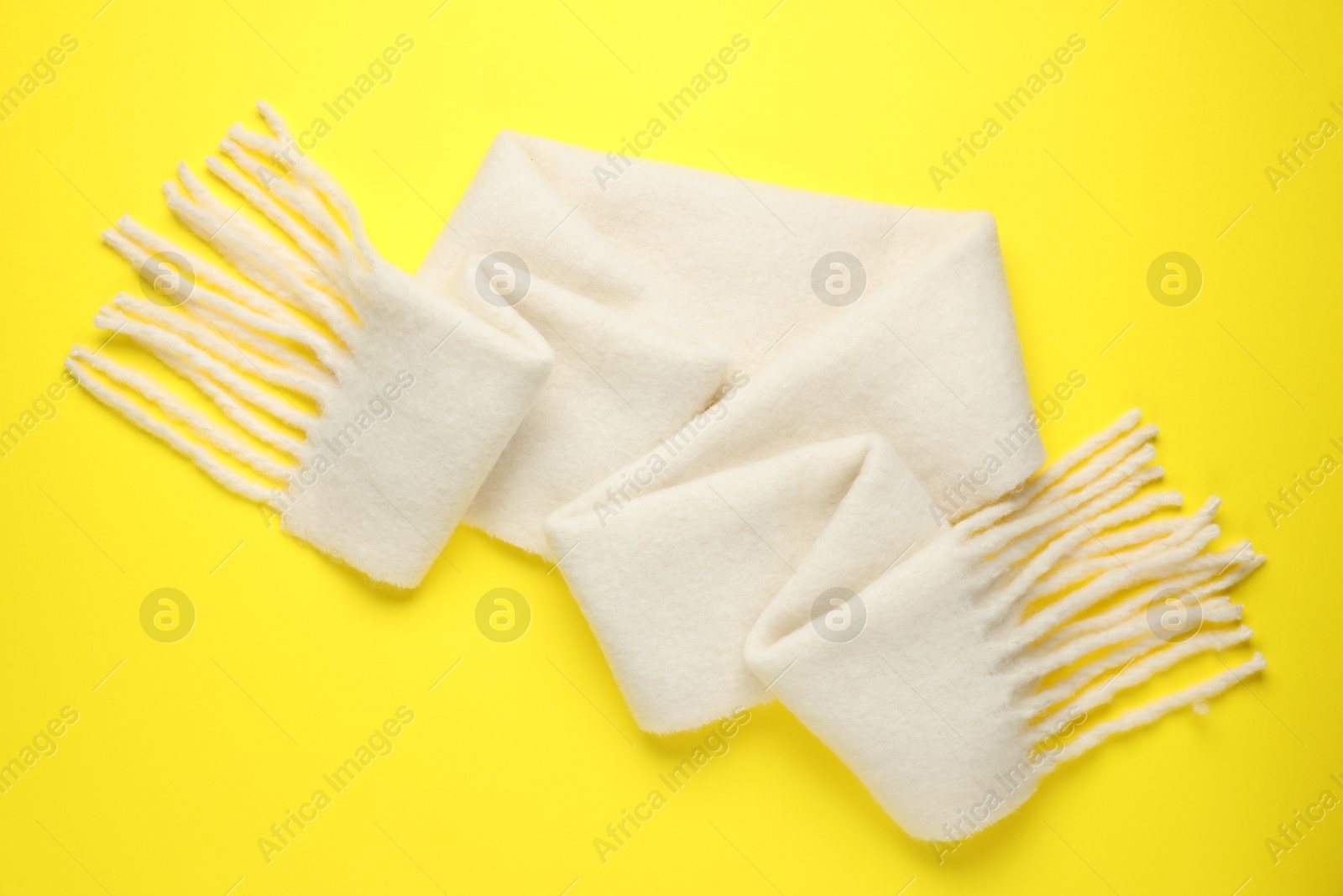 Photo of Warm woolen scarf on yellow background, top view