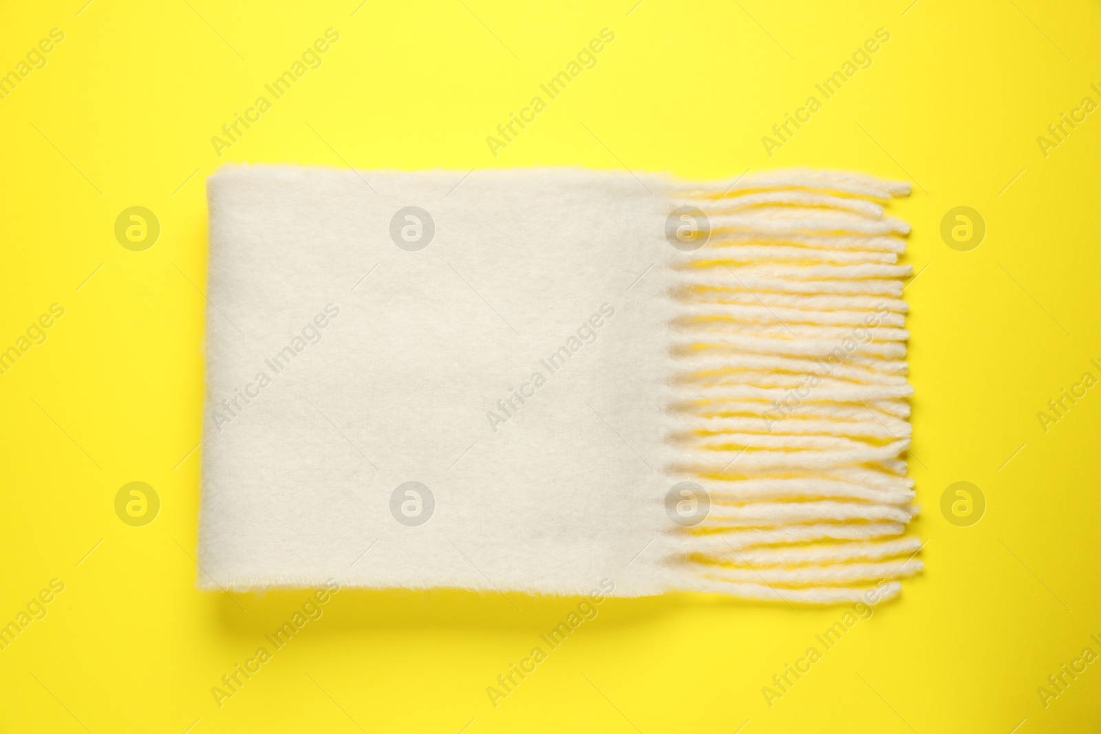 Photo of Warm woolen scarf on yellow background, top view