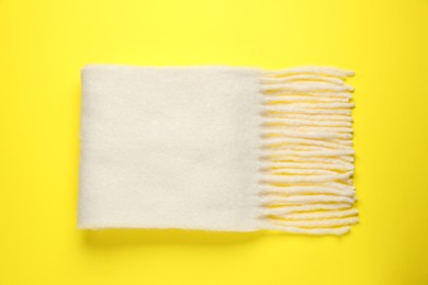 Photo of Warm woolen scarf on yellow background, top view