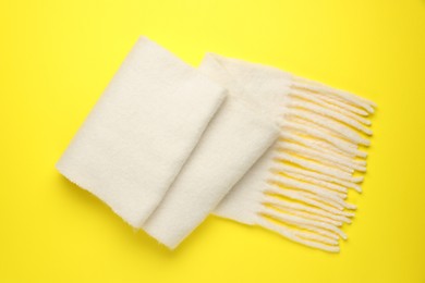 Photo of Warm woolen scarf on yellow background, top view