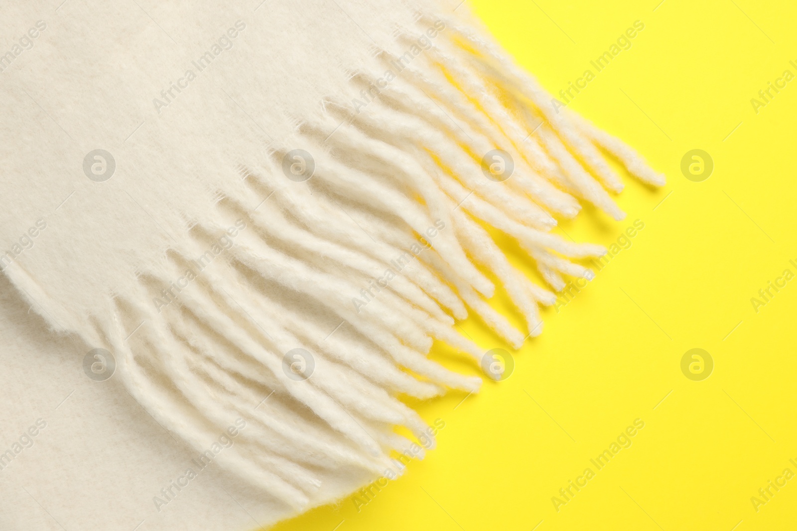 Photo of Warm woolen scarf on yellow background, top view