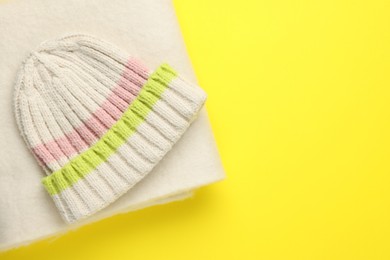 Photo of Warm woolen hat and scarf on yellow background, top view. Space for text