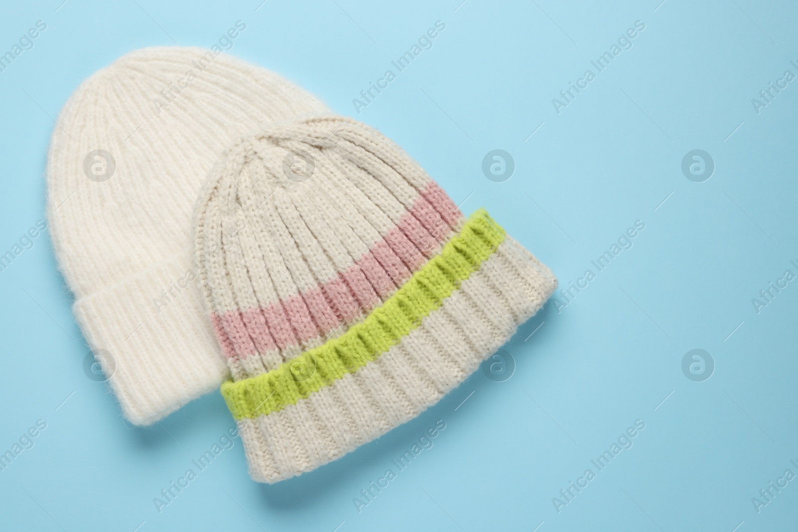 Photo of Warm woolen hats on light blue background, top view