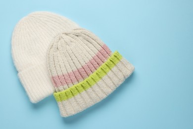 Photo of Warm woolen hats on light blue background, top view